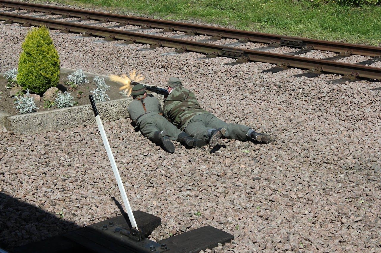 A member in field uniform lying prone beside a railway track