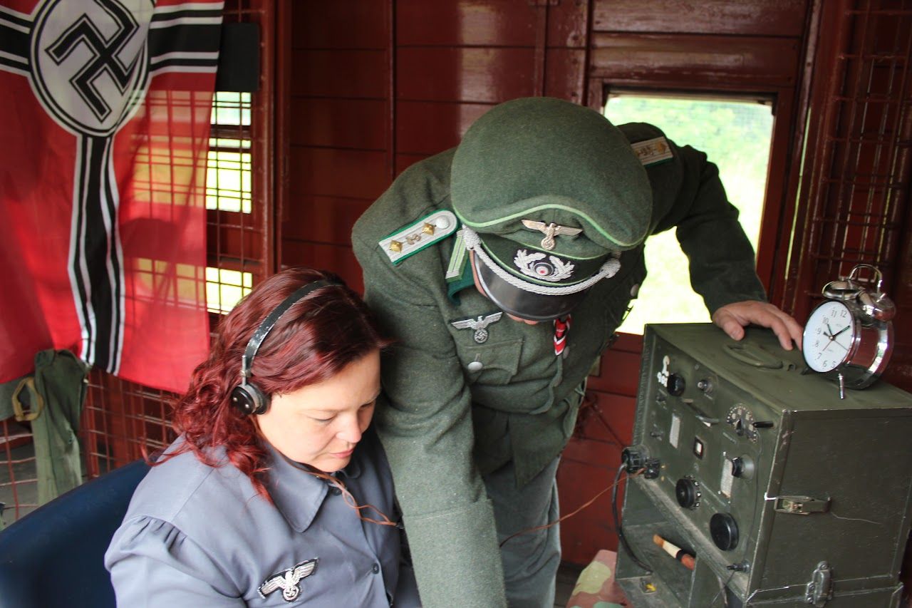 A Helferin wearing headphones at a radio set while an officer looks on