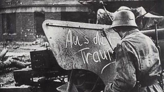 A German soldier chalking “Aus der Traum” on the shield of an abandoned American gun