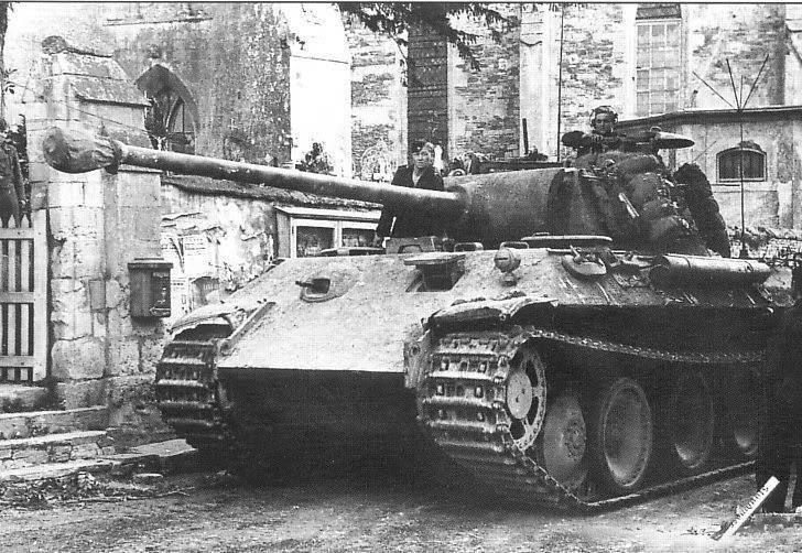 A Panther tank of the Panzer Lehr Division beside a stone church wall in a Normandy village