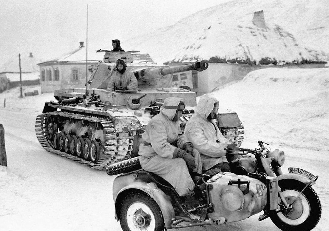 A Panzer IV and a sidecar motorcycle in deep snow, crews in white winter camouflage