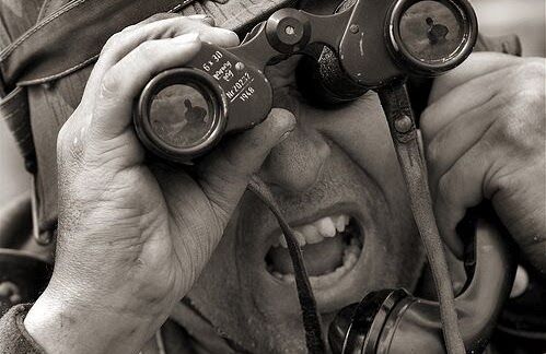 Close-up of a man in field uniform looking through binoculars