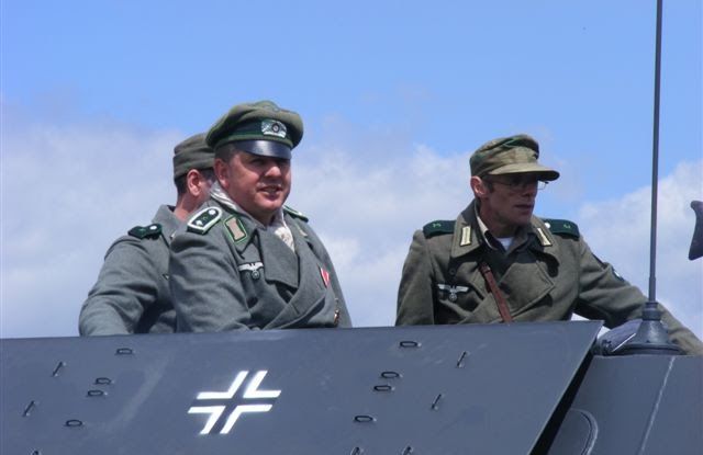 Two officers in peaked caps aboard a half-track