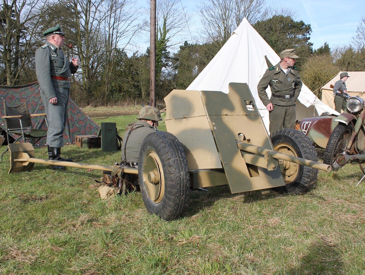 Members in field uniform beside a 3.7 cm PaK 36 anti-tank gun in front of a tent